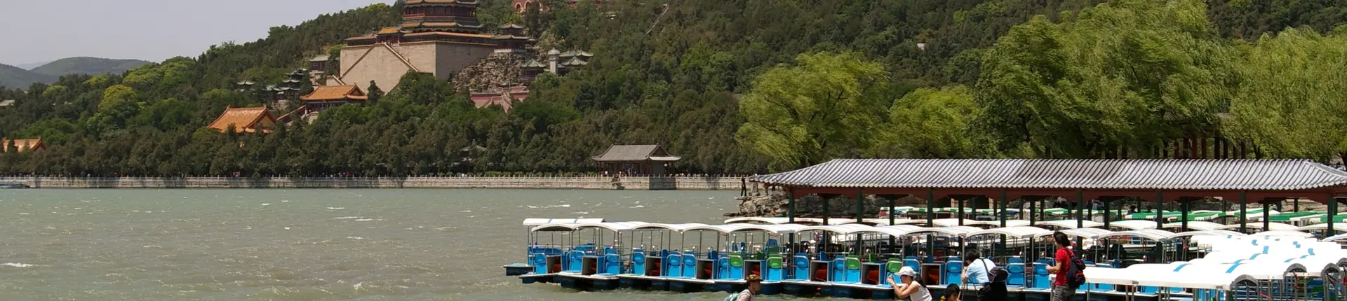 Sightseeing boats on Kunming Lake below wooded hills at the Summer Palace, Beijing