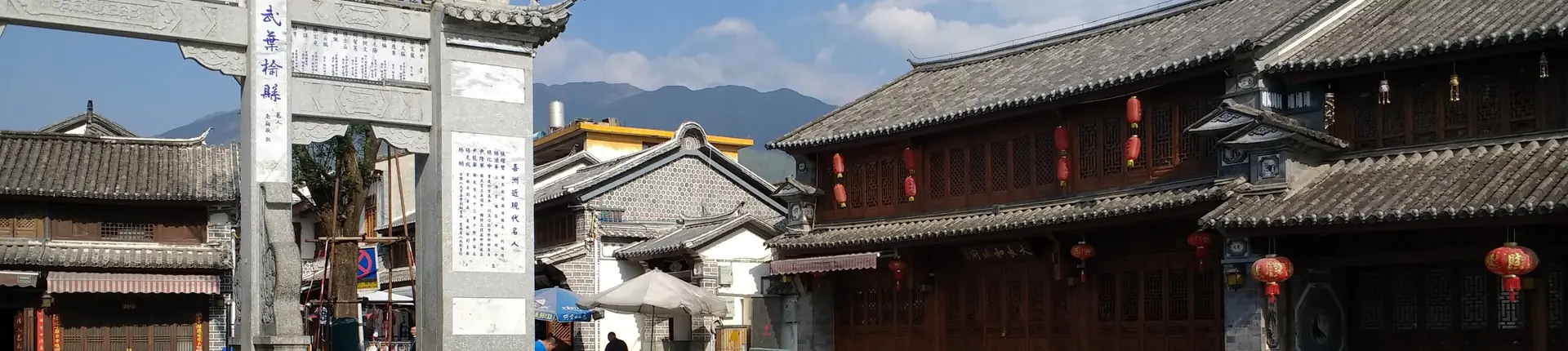 Traditional Yunnan buildings with dark tiled roofs and a stone gateway