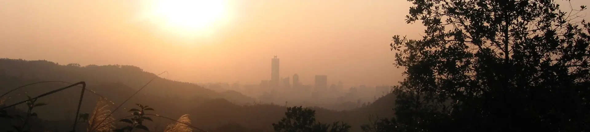 Layered hills and a distant city skyline in hazy sunset light from Baiyun Mountain, Guangzhou