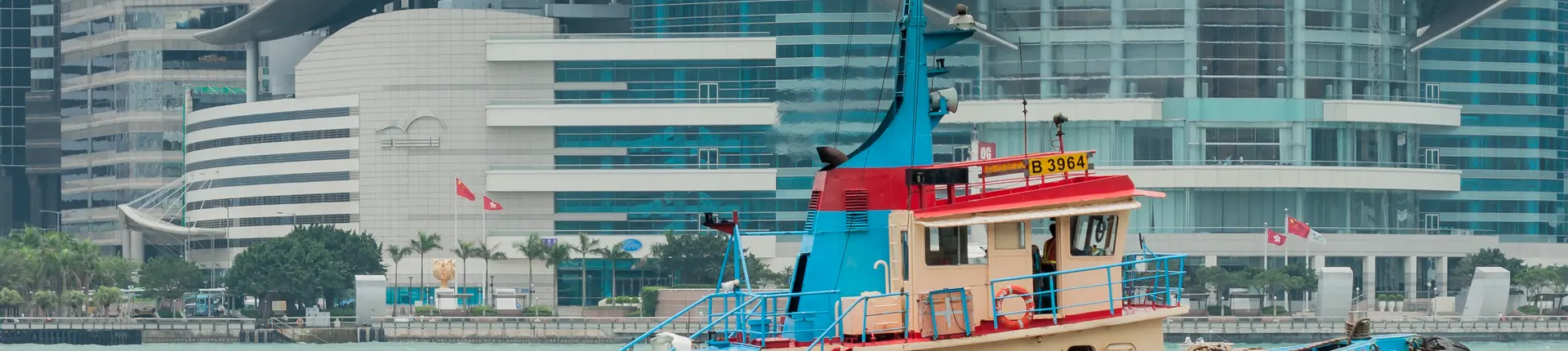 Green-and-white passenger ferry beside waterfront towers in Victoria Harbour, Hong Kong