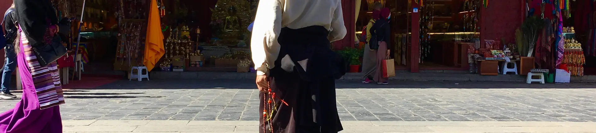 Visitor in dark clothing outside a temple entrance along Barkhor Street, Lhasa