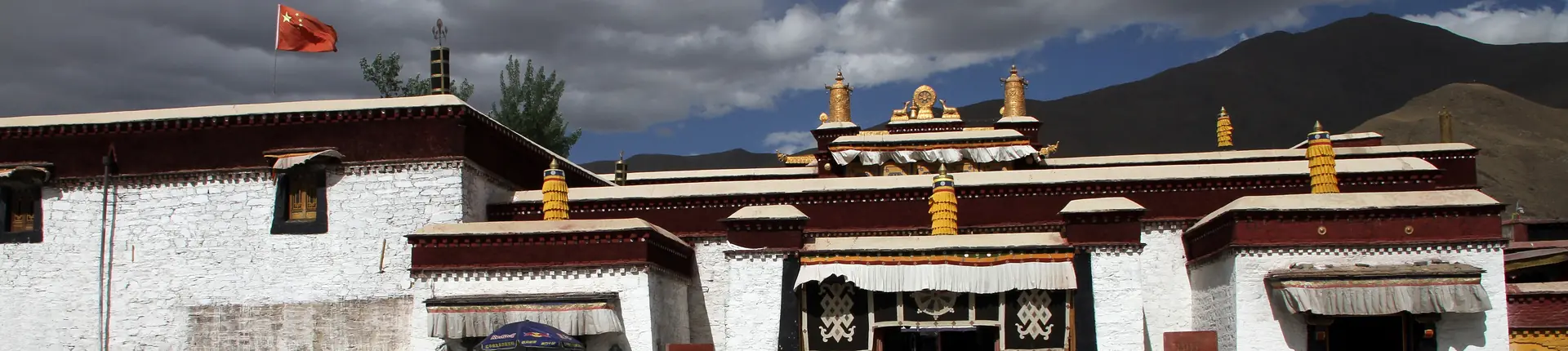 White monastery walls and a gold-trimmed gateway at Trandruk Monastery, Tibet