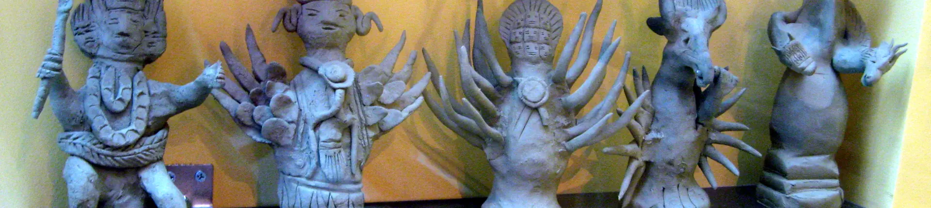Blue sculpted figures with elaborate headdresses displayed against a gold backdrop