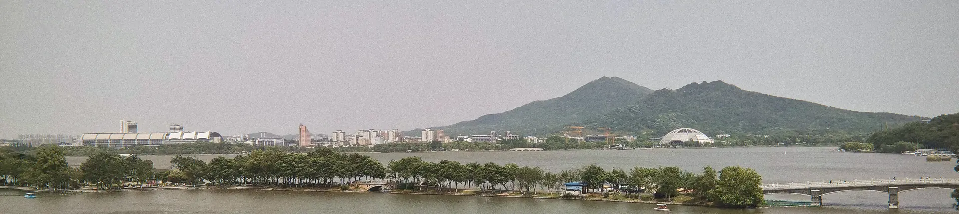 Lakeside paths and a low bridge beneath distant hills at Xuanwu Lake, Nanjing