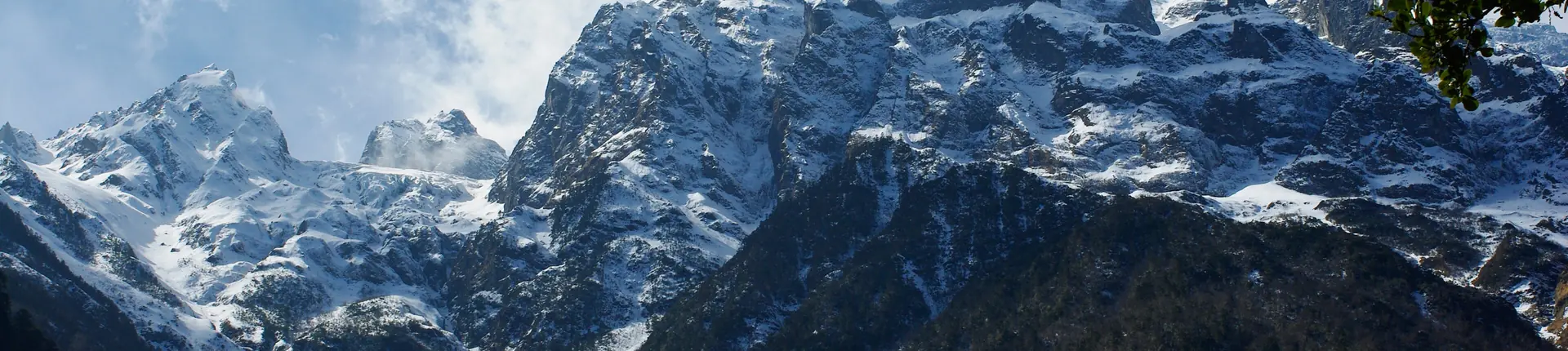 Snow-covered mountain ridges above a dark forest near Mingyong Glacier in Yunnan