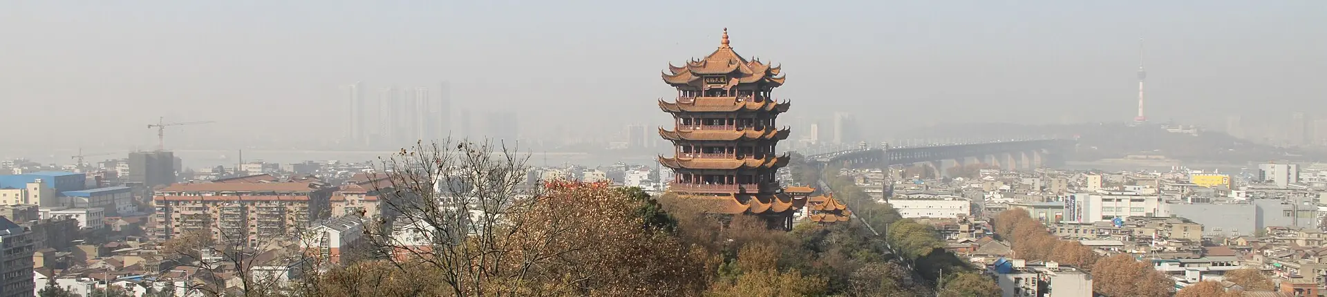 Yellow Crane Tower rising above Wuhan rooftops against a hazy skyline