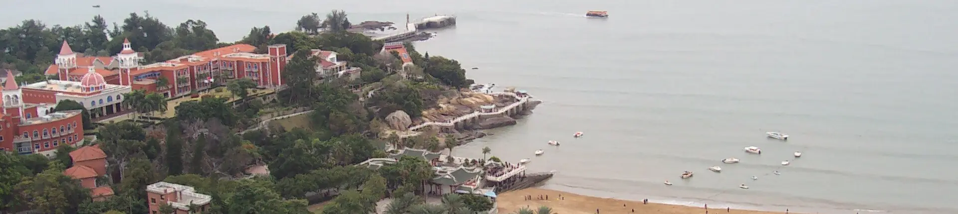 Sandy shoreline and red-roofed waterfront buildings along Huandao Road, Xiamen