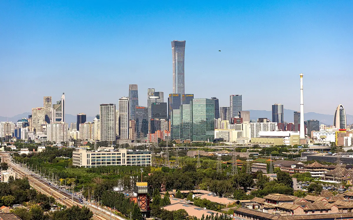 Beijing skyline with the tall CITIC Tower above green trees under a clear sky