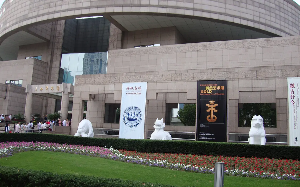 Shanghai Museum's stone facade beside flowerbeds and a green lawn