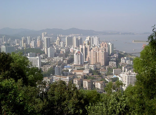 Les tours d'habitation et le littoral de Zhuhai visibles au-delà d'une colline verdoyante et boisée