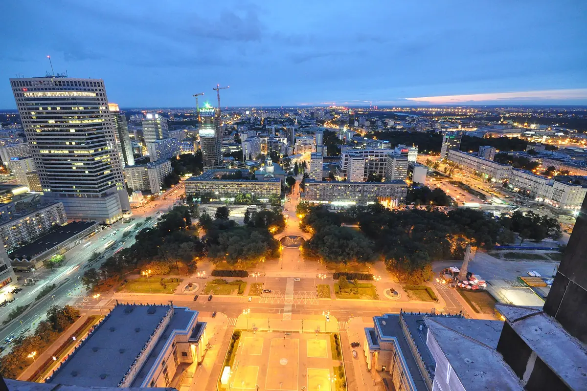 Beijing city buildings and avenues illuminated around a green plaza at dusk