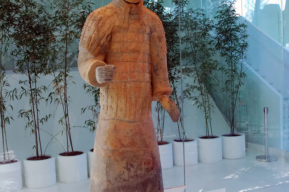 Statue eines Terrakotta-Kriegers in einem Innenraum neben einem Bambus im Topf