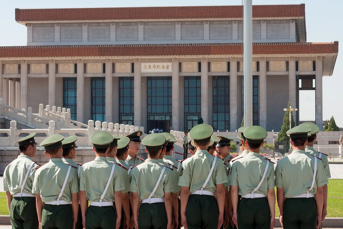 Group of uniformed personnel standing before the Great Hall of the People