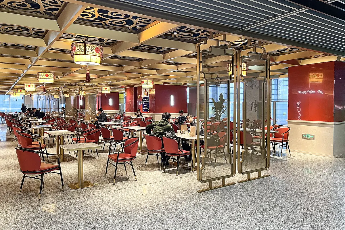 Restaurant tables and red chairs beneath patterned ceiling panels