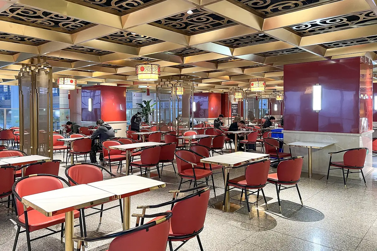Spacious restaurant dining room with red chairs and ornate wooden ceiling beams