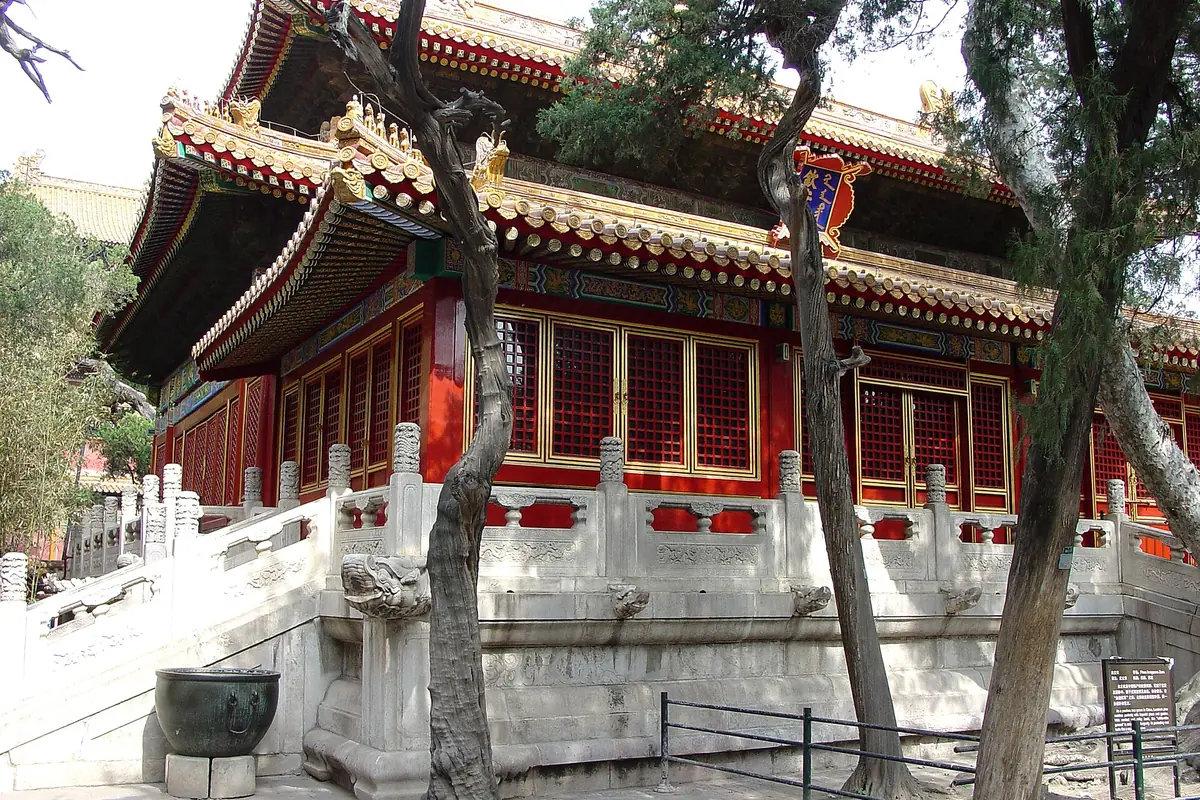 Red traditional pavilion with ornate roof beams above carved stone balustrades