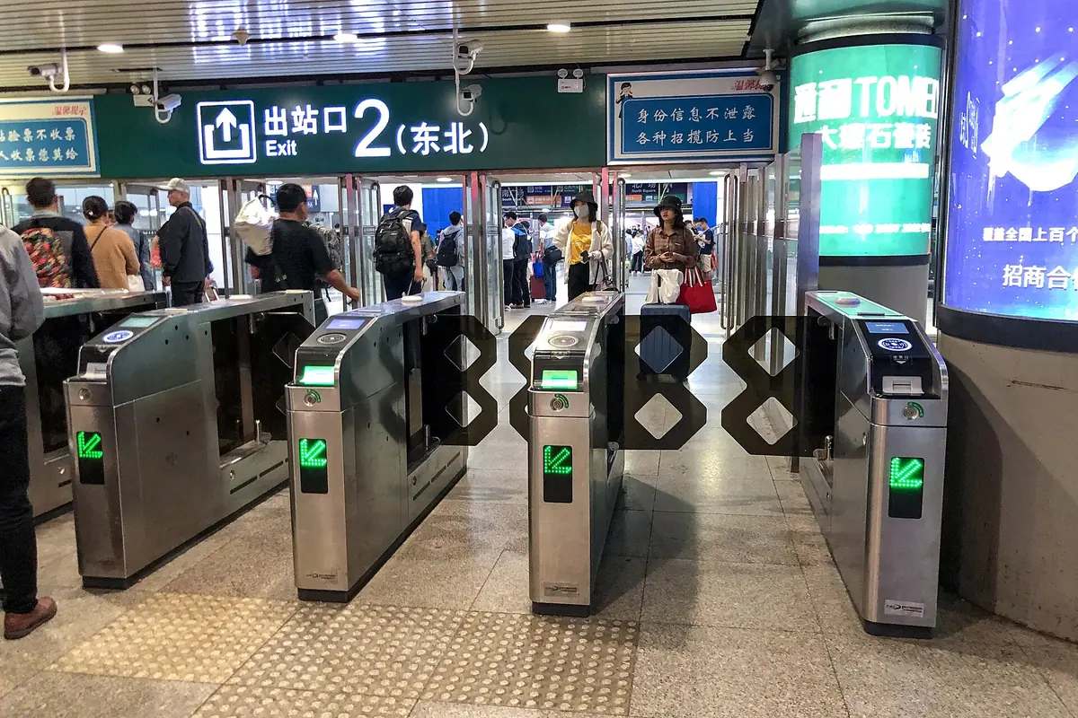 Railway ticket gates with green arrows beneath an exit-two sign