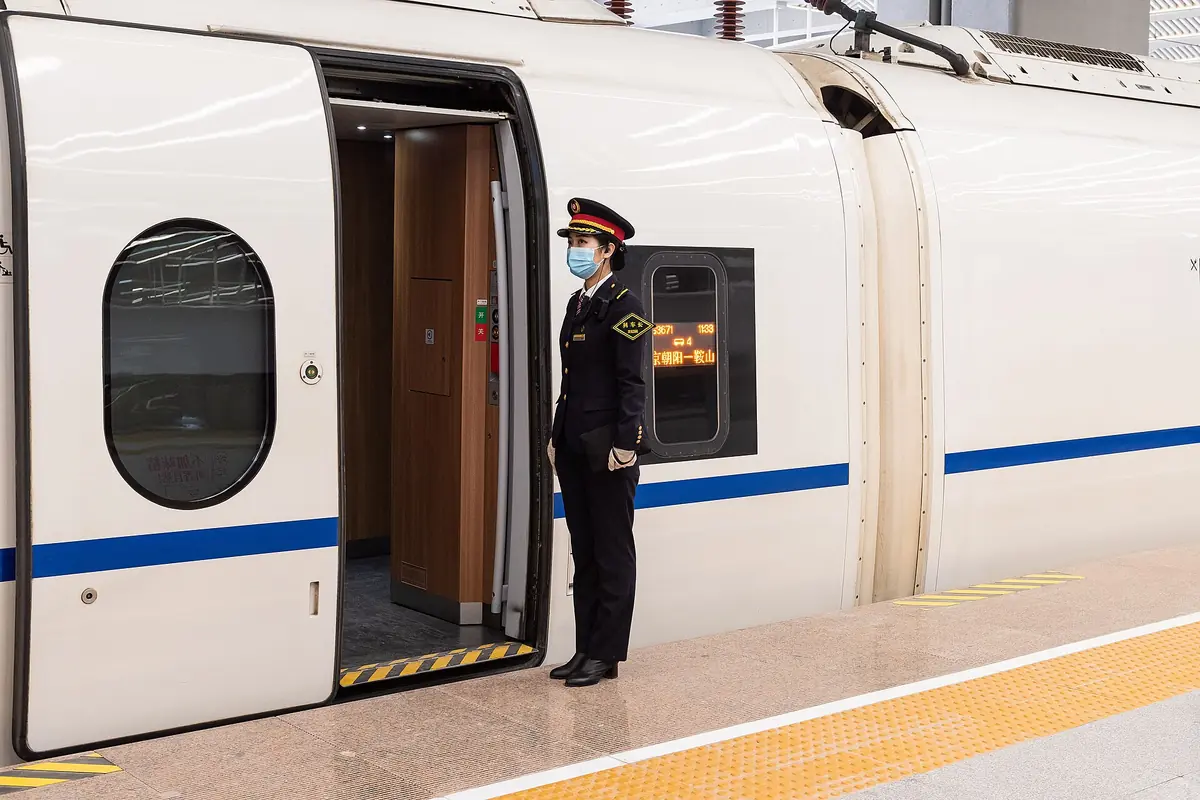Uniformed railway attendant beside an open high-speed train door