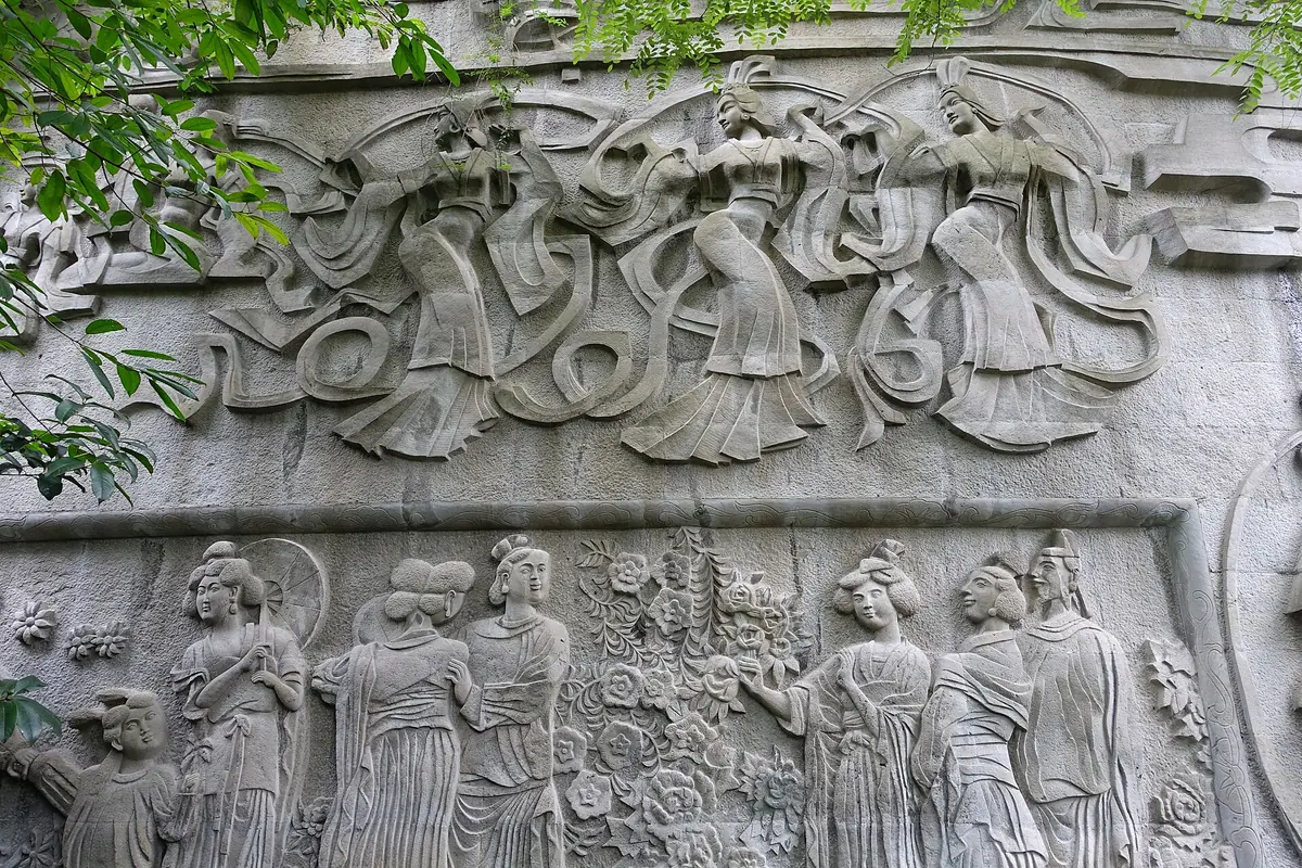 Stone relief depicting musicians and figures beneath carved clouds and ribbons