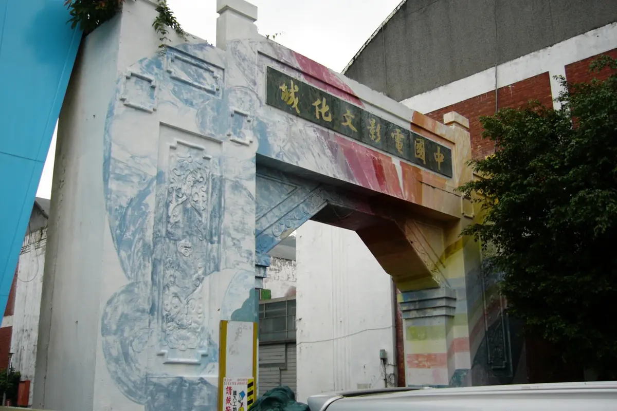 Concrete gateway decorated with pale blue artwork beside green trees