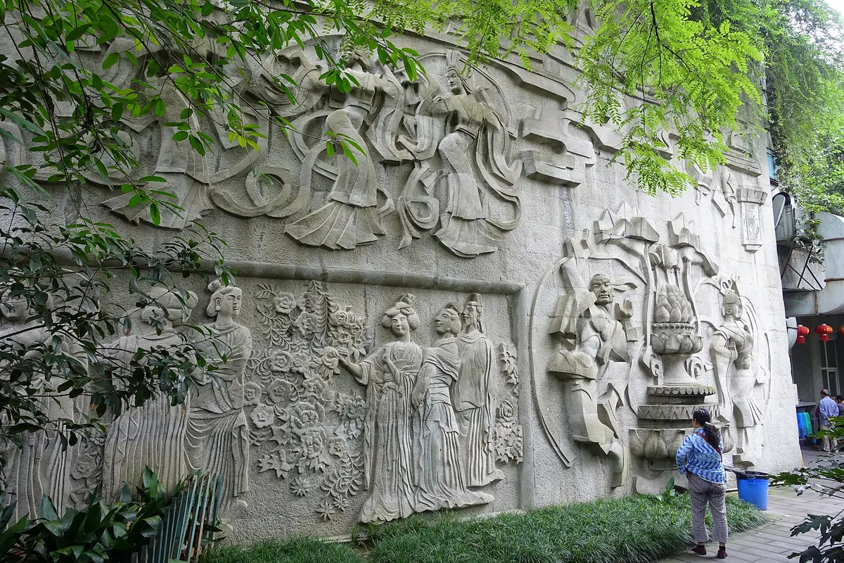 Visitors beside a long stone relief depicting musicians and historical figures