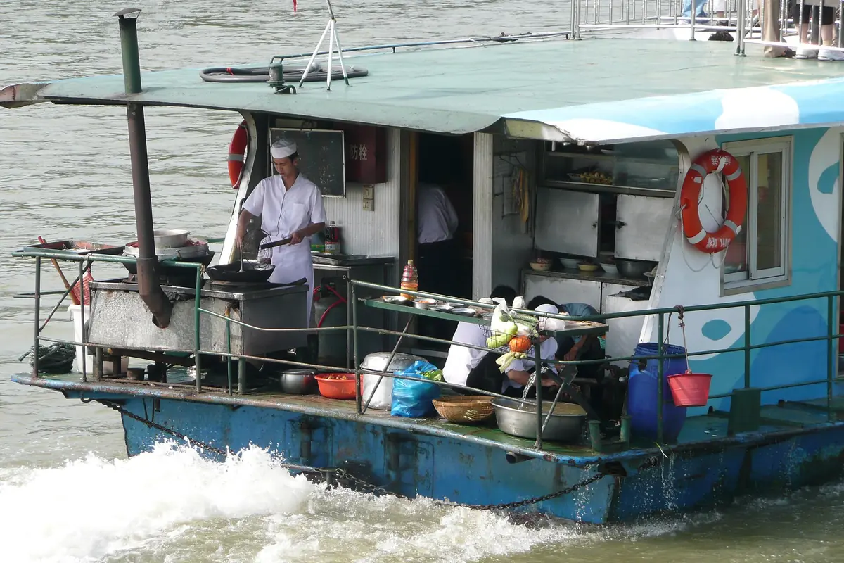 Person aboard a small blue motorboat with life rings and containers beside the engine