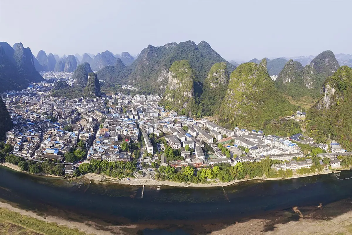 Vue panoramique d’une ville au bord de l’eau entourée de hauts pics karstiques