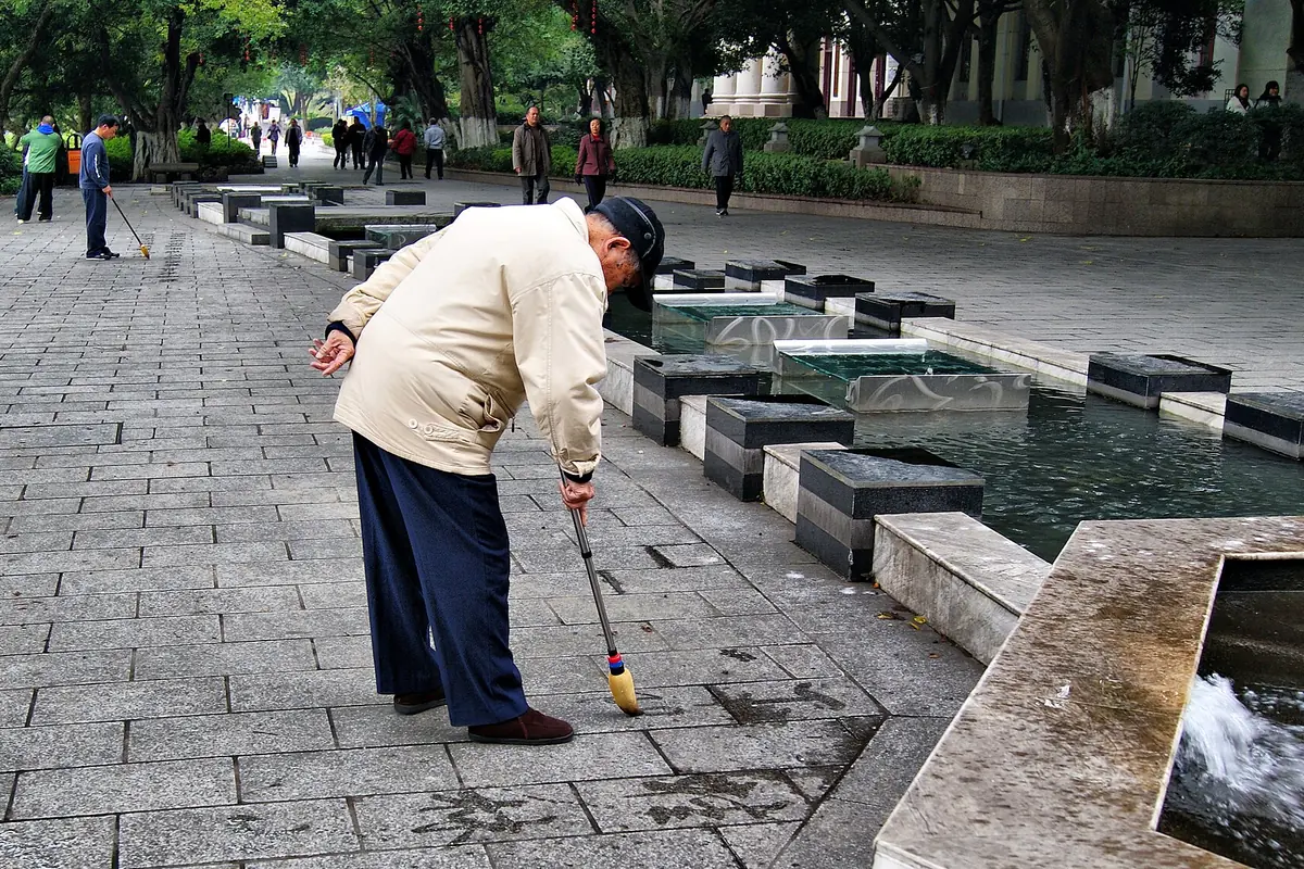 Man using a long-handled toy beside a row of park water features