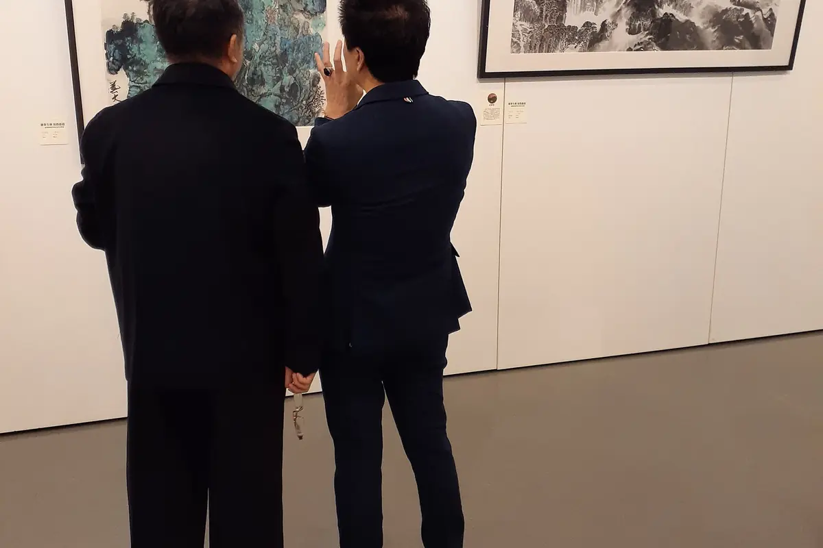 Zwei Besucher betrachten gerahmte Exponate an einer beleuchteten Museumswand