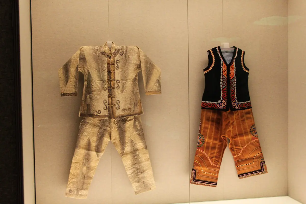 Vêtement brodé clair et tenue orange et noire exposés côte à côte