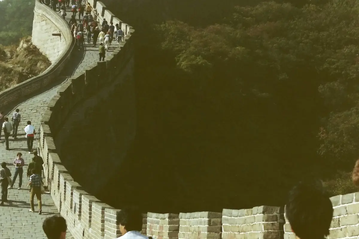 Historic photograph of visitors walking along Great Wall battlements on a wooded hillside