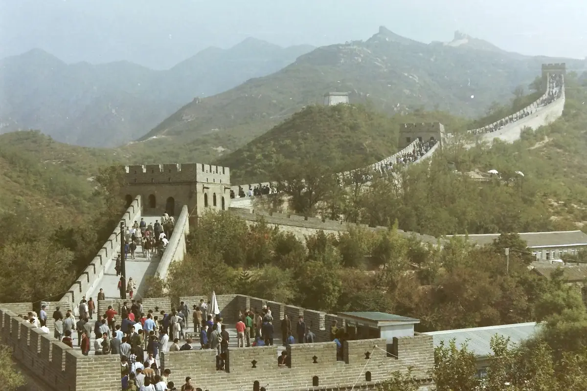 Belebter Fußweg auf der Chinesischen Mauer mit Steintürmen auf nebligen grünen Bergen