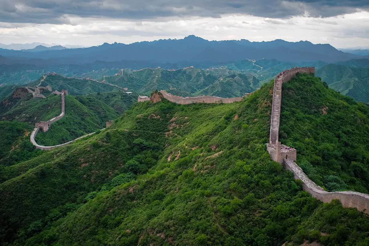 Remparts de la Grande Muraille traversant des crêtes montagneuses verdoyantes densément boisées