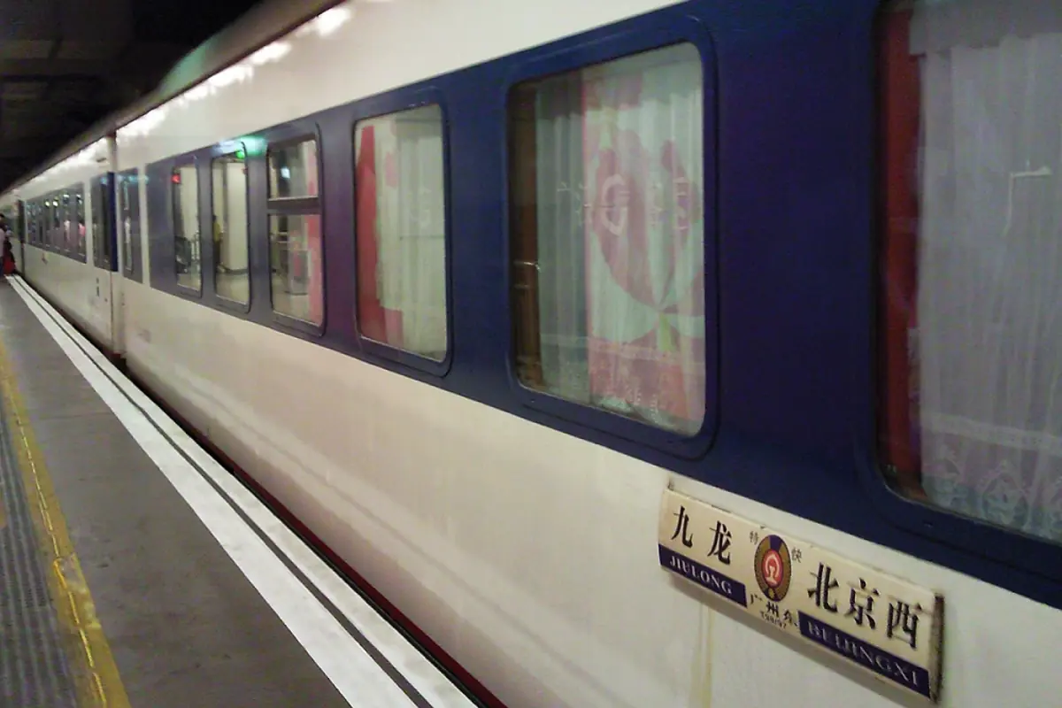 Passenger train with dark windows and advertisements beside a station platform