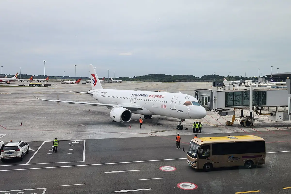China Eastern aircraft at a boarding bridge with an airport bus nearby