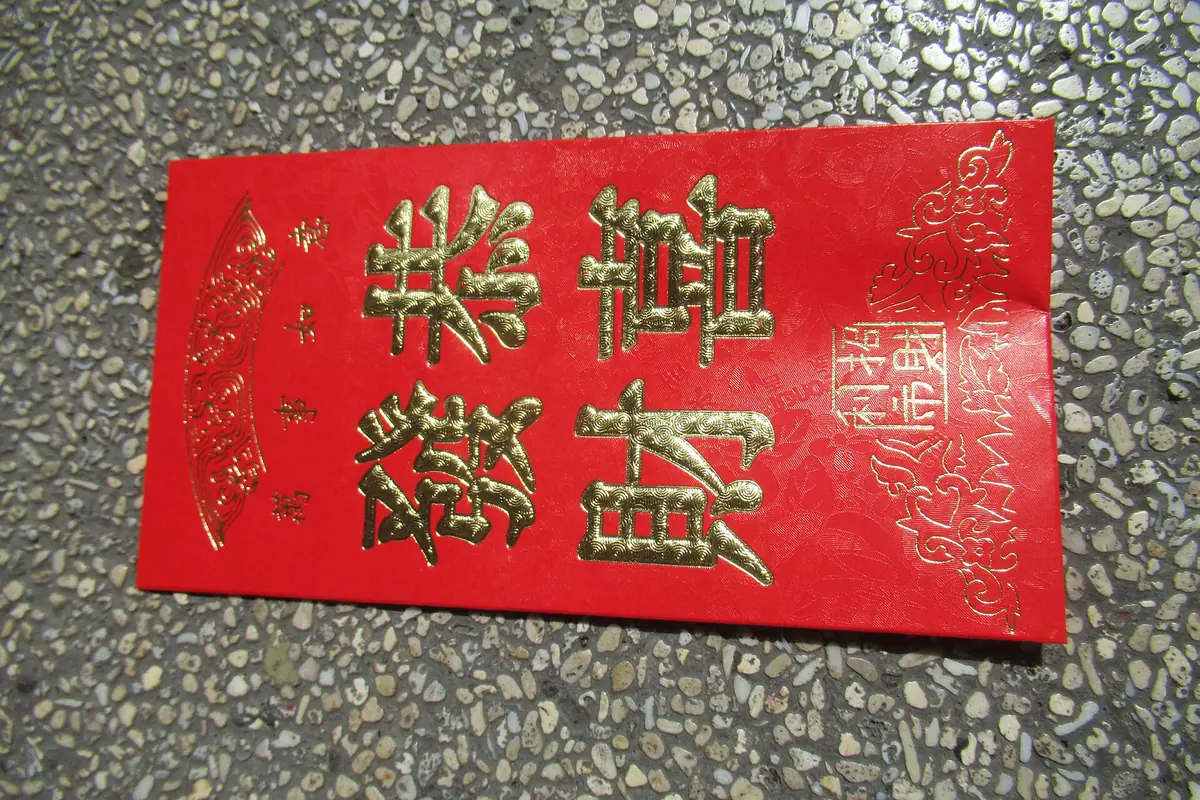 Roter Umschlag mit goldenen chinesischen Schriftzeichen auf einer gesprenkelten Oberfläche