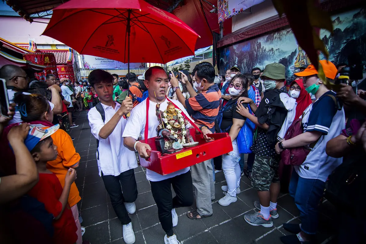 Street procession carrying a small ceremonial shrine beneath red umbrellas