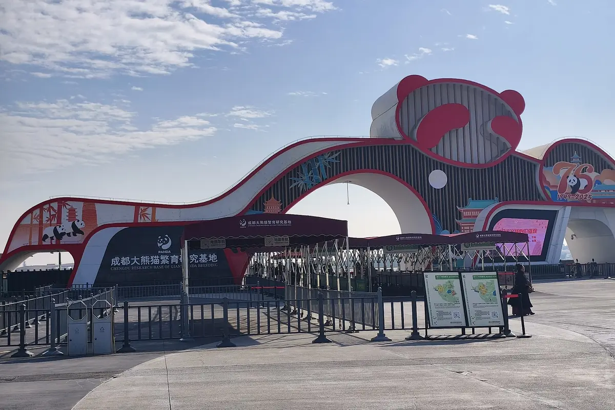 Large red animal-shaped entrance arch above metal ticket barriers at a visitor attraction