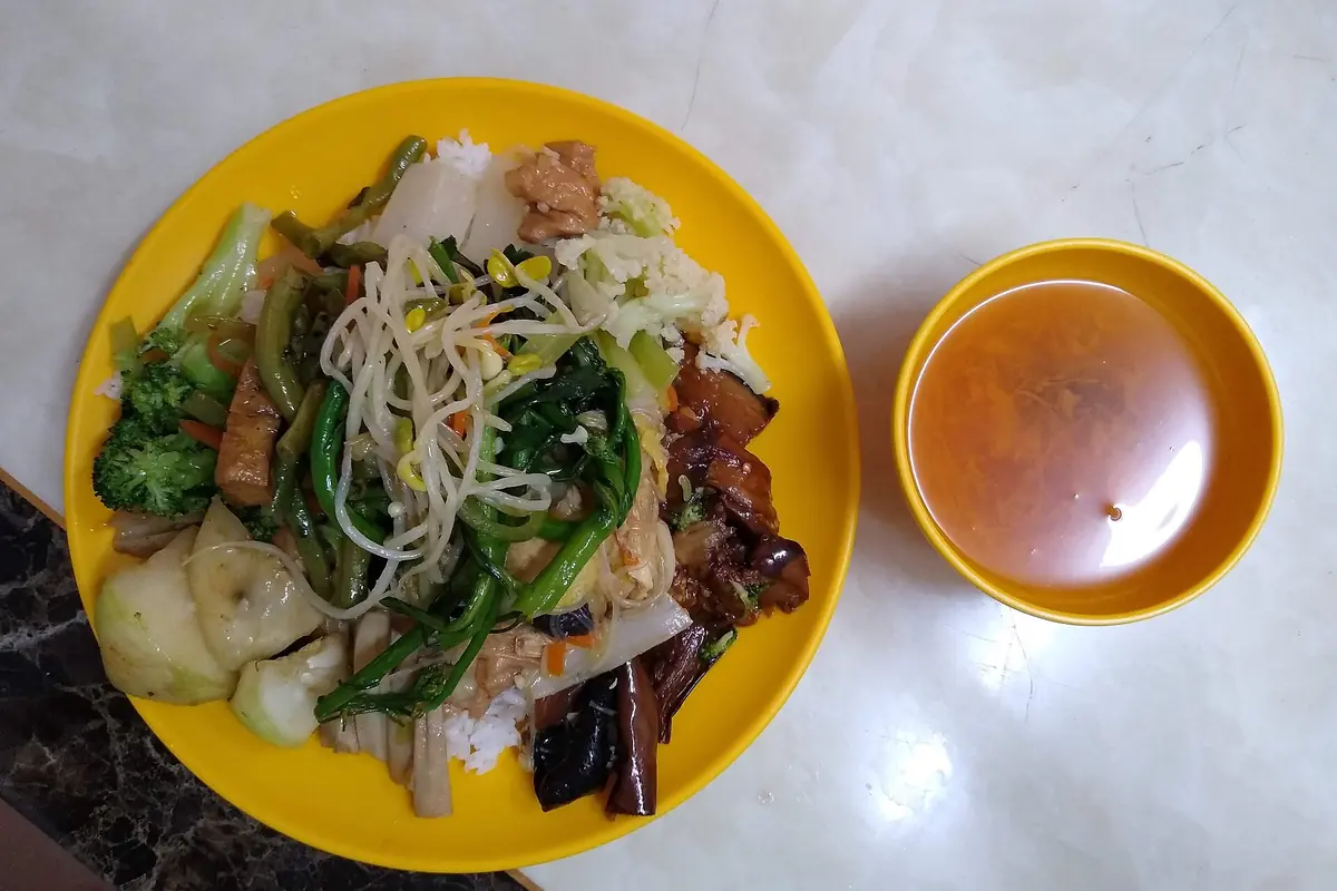 Plate of rice, vegetables and meat beside a small bowl of soup