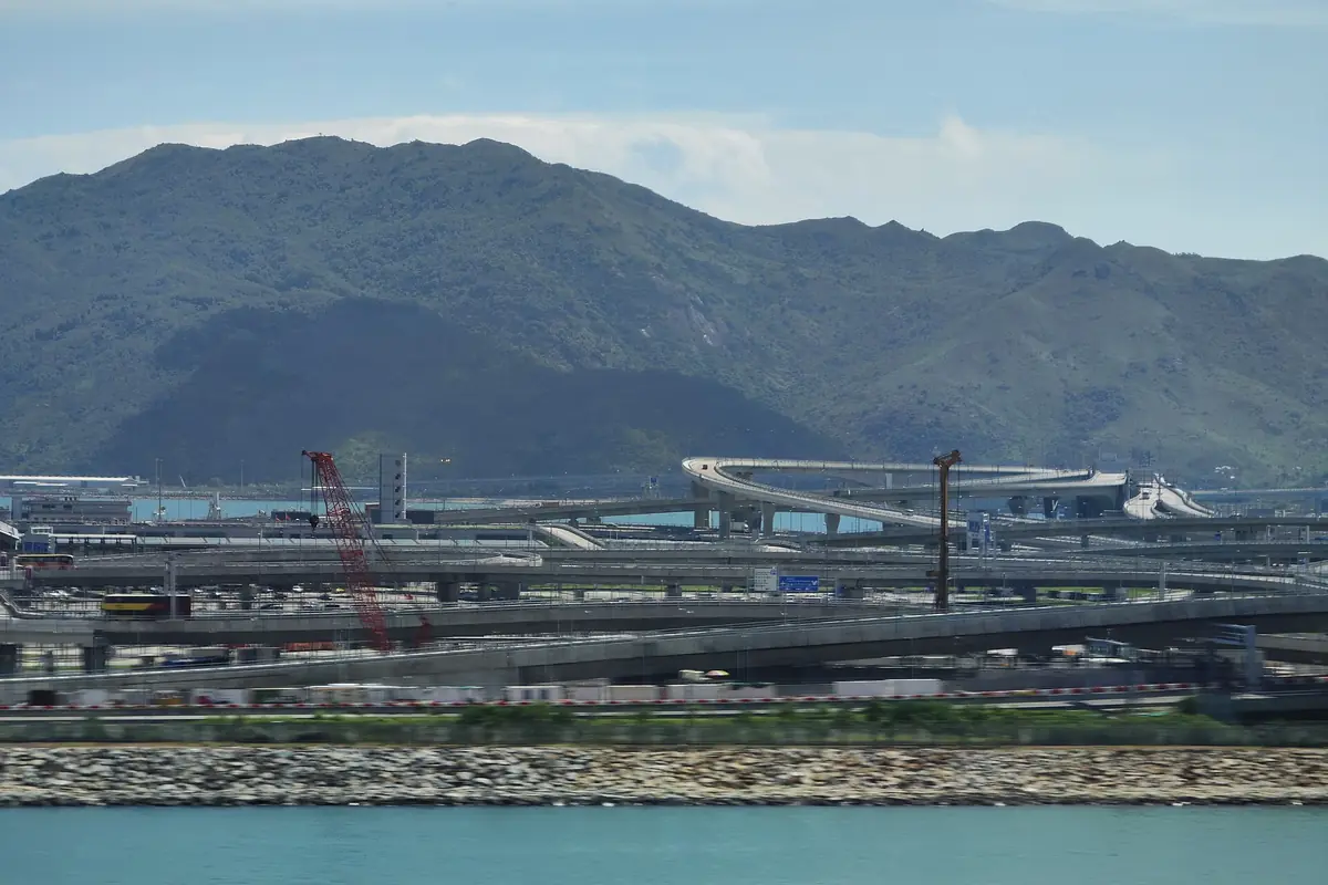 Pistes d'aéroport et bâtiments du terminal au bord de l'eau, avec des montagnes à l'horizon
