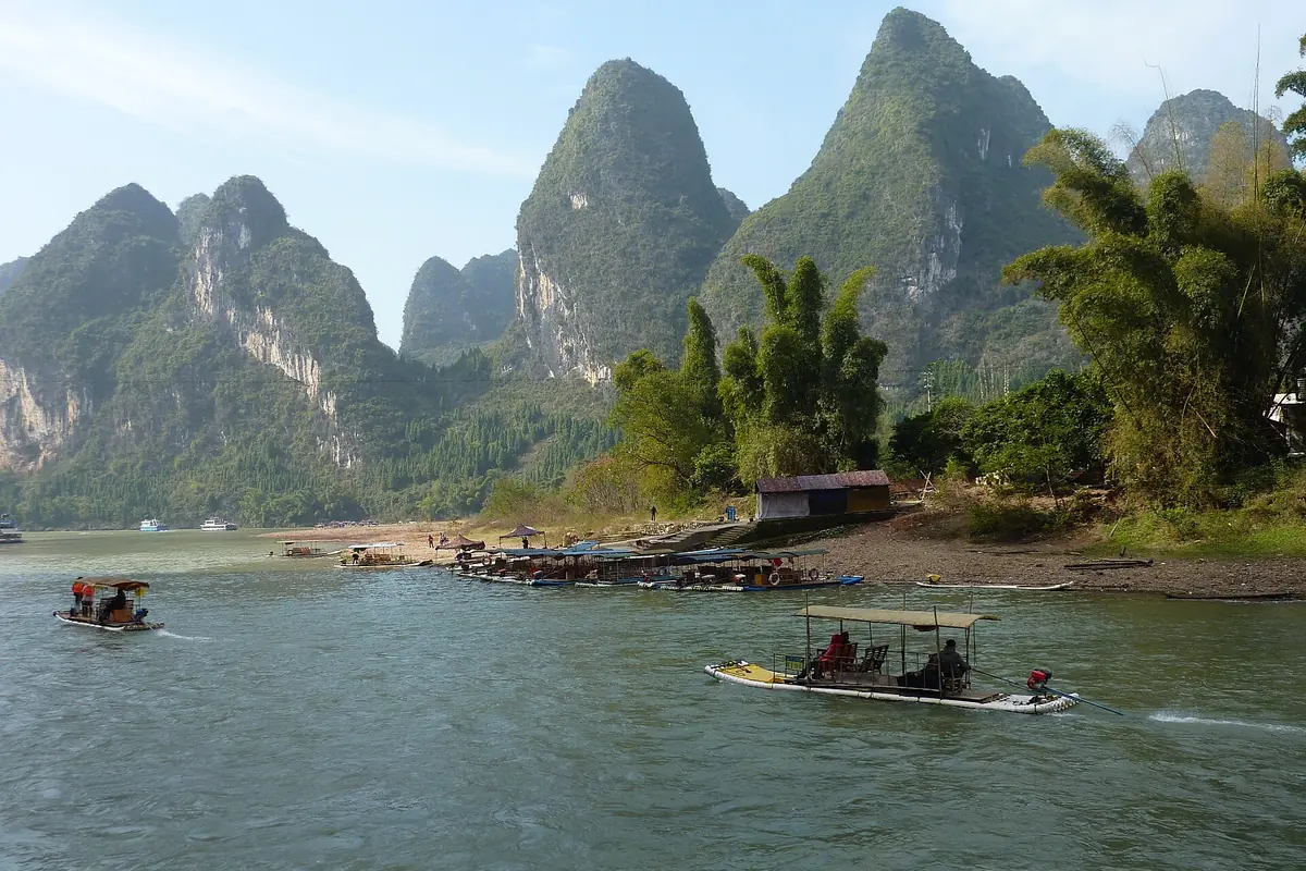 Bamboo rafts on a river beneath tall karst peaks and green trees