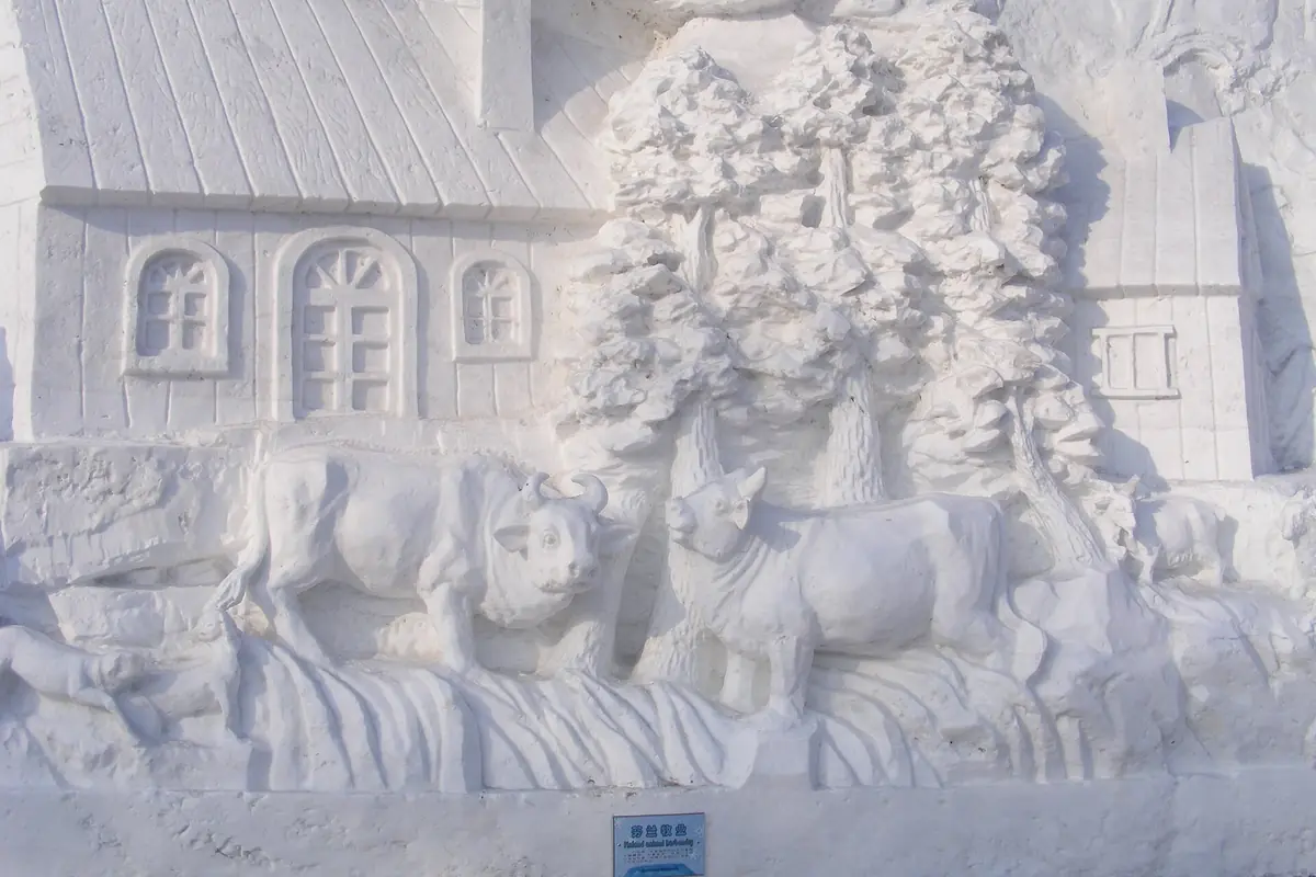 Weiße Schneeskulptur mit Tieren, Bäumen und einem traditionellen Haus