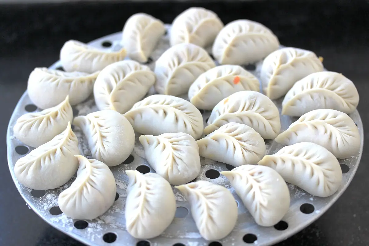 Petits pains blancs à la vapeur, plissés et disposés sur un plateau rond perforé