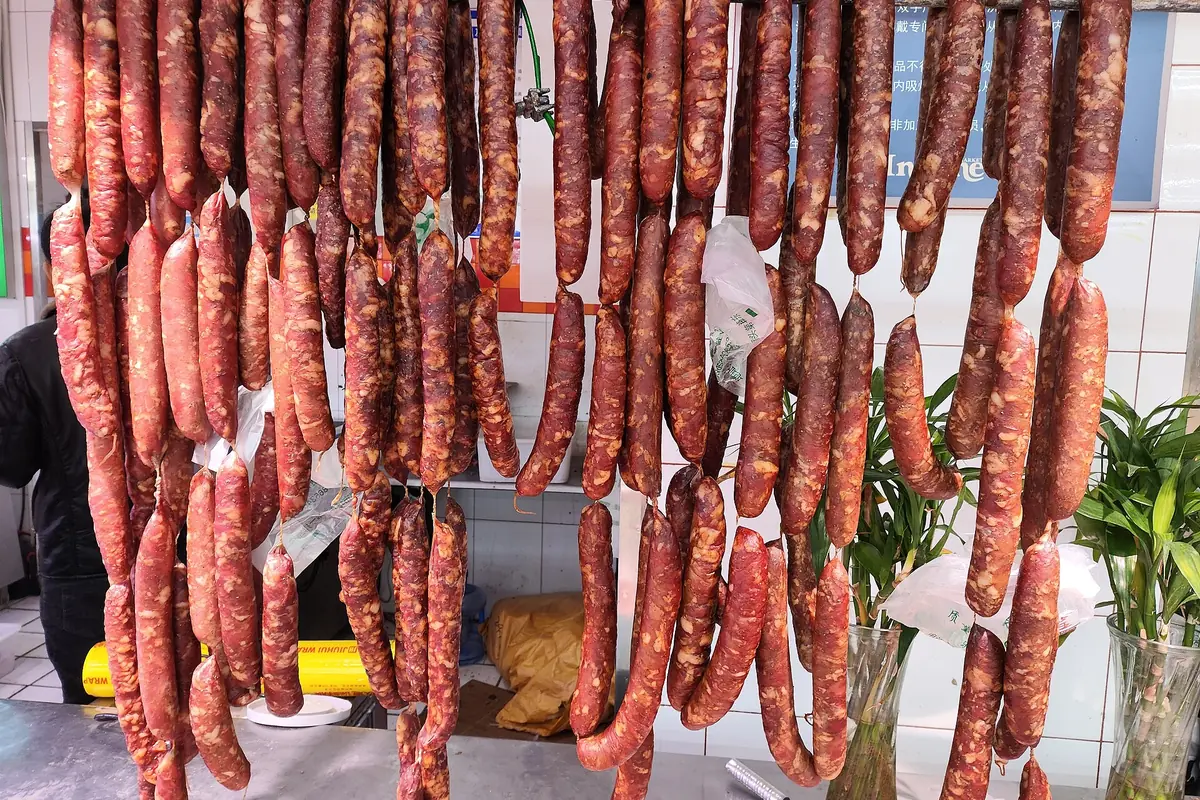 Rangées de saucisses séchées rouges suspendues à l’extérieur d’une boutique alimentaire