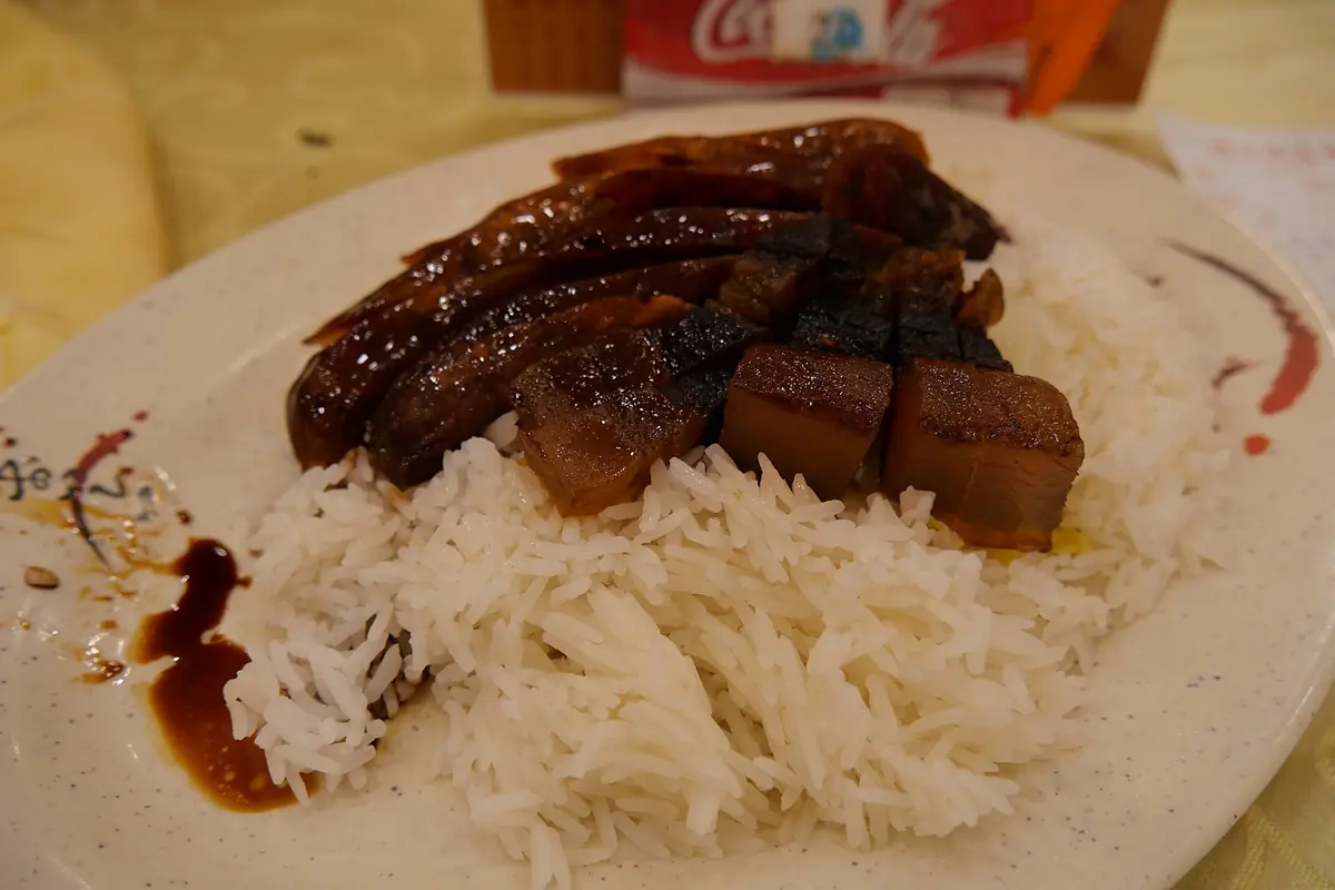 Braised pork slices in dark sauce beside a mound of white rice