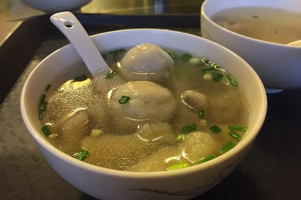 Soupe aux boulettes de poisson et à la ciboule hachée dans un bol blanc