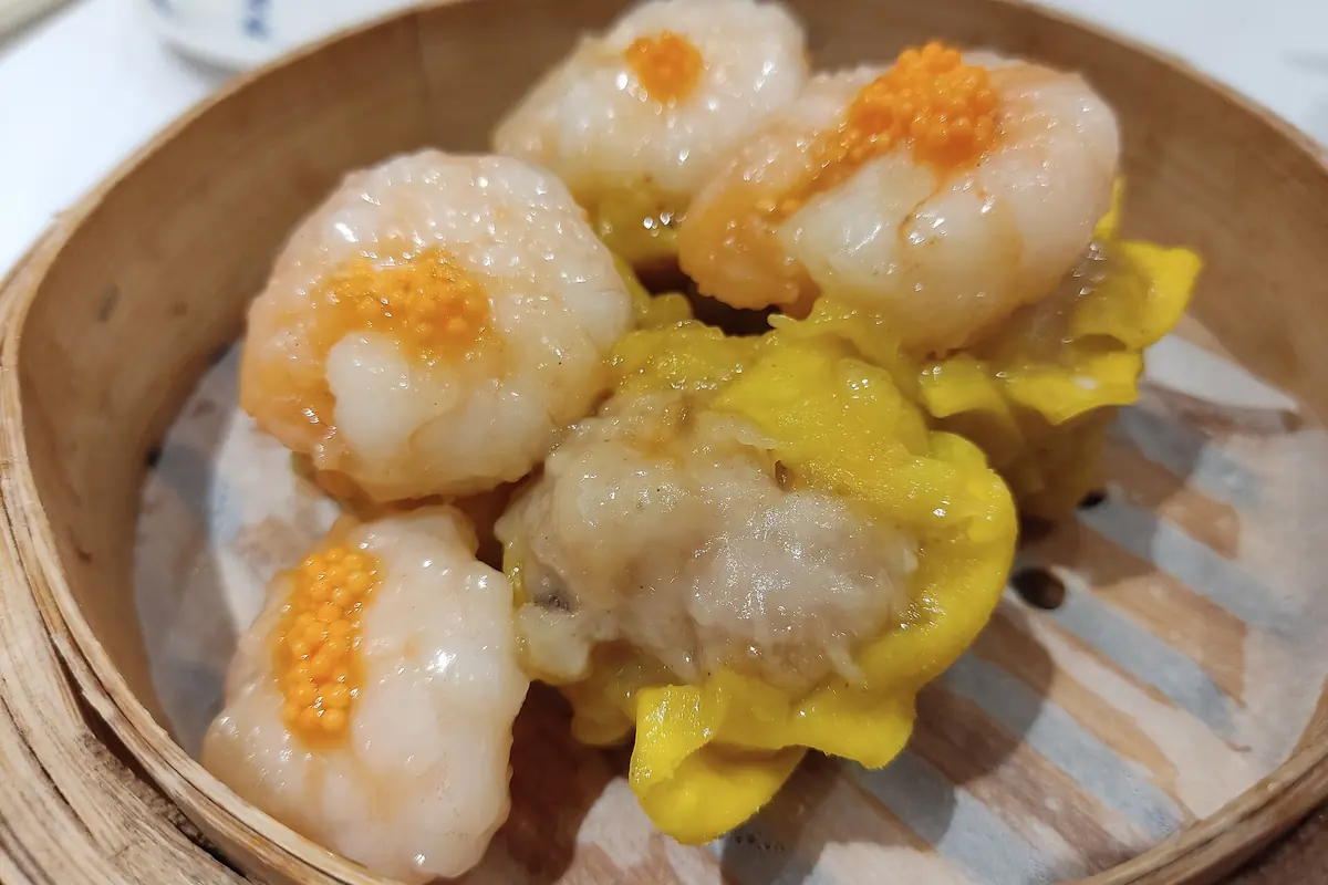 Raviolis shumai au cœur orange dans un panier vapeur rond en bambou
