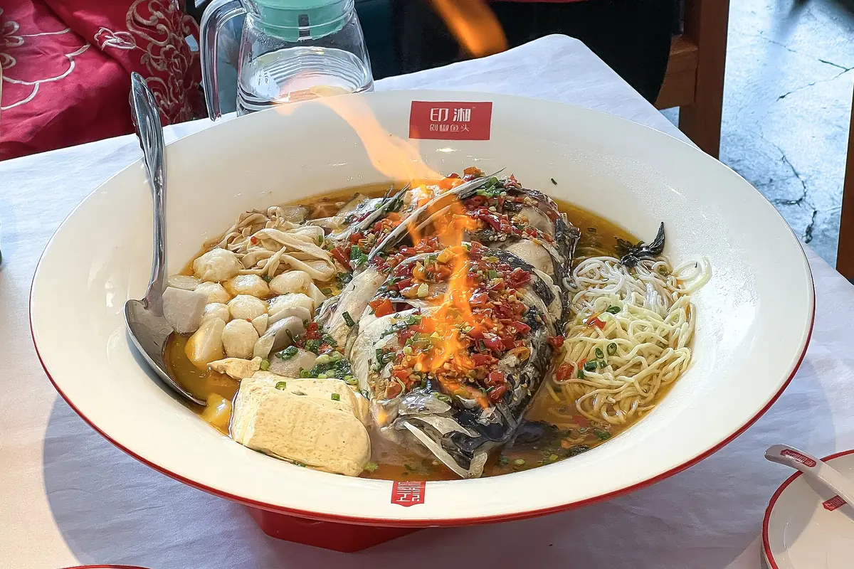 Fish, noodles, tofu and chopped vegetables served together in a white bowl