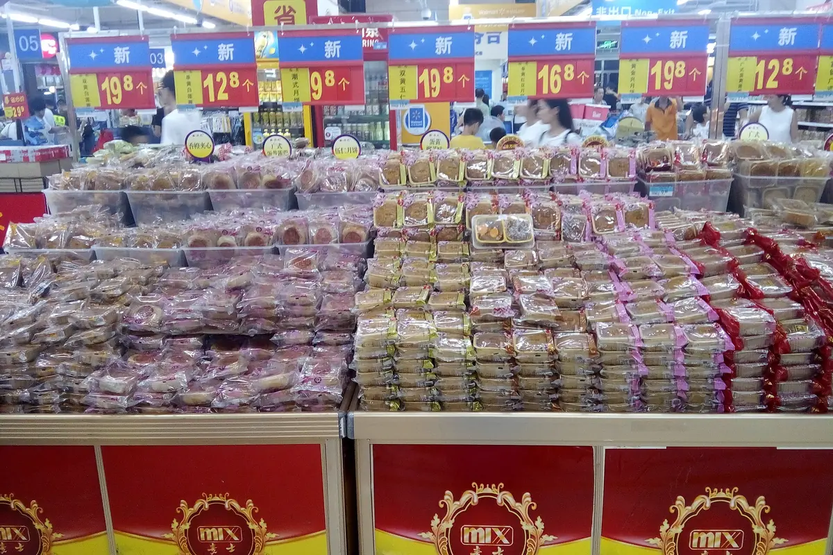 Rows of packaged sweets and snacks displayed beneath colorful price signs in a shop