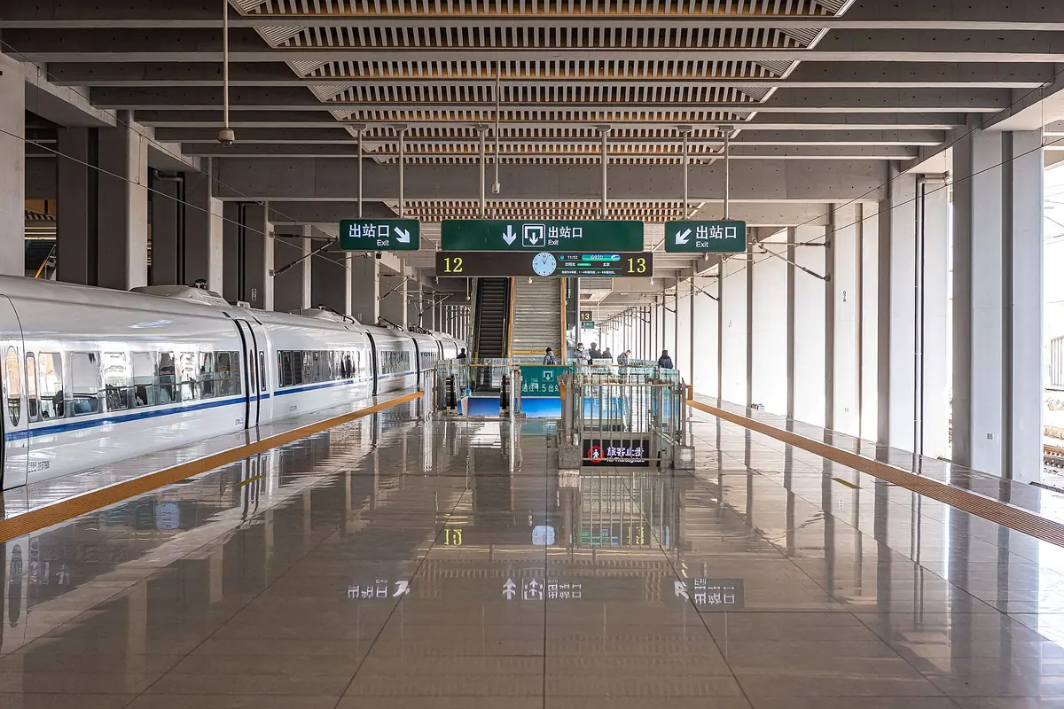 Empty station platform with white columns and a reflective tiled floor